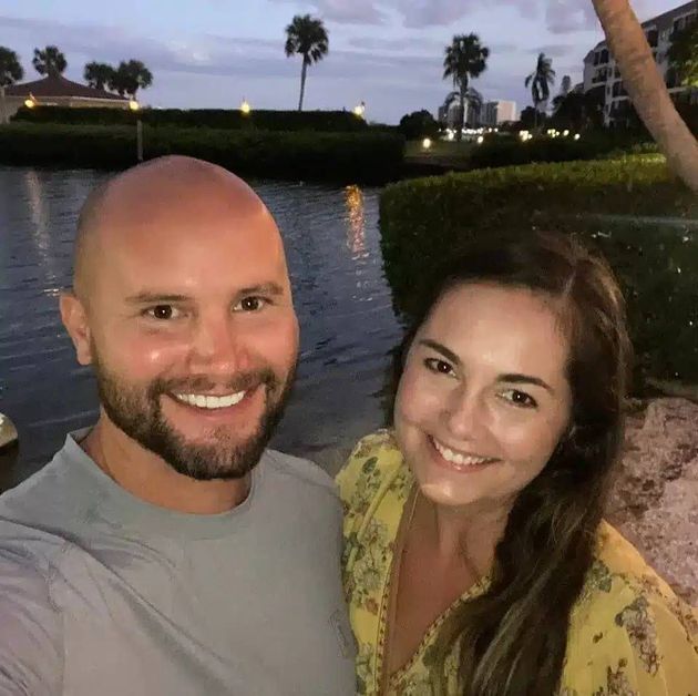 A man and a woman are posing for a picture in front of a body of water.