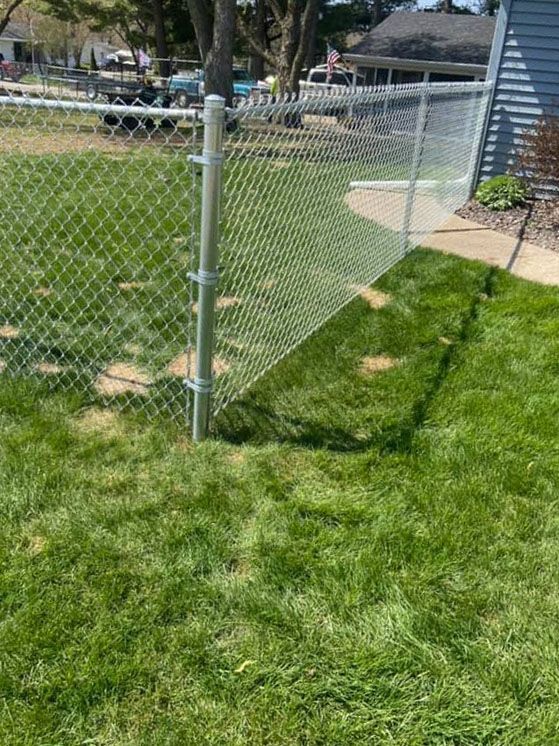 A chain link fence is sitting in the middle of a lush green yard.