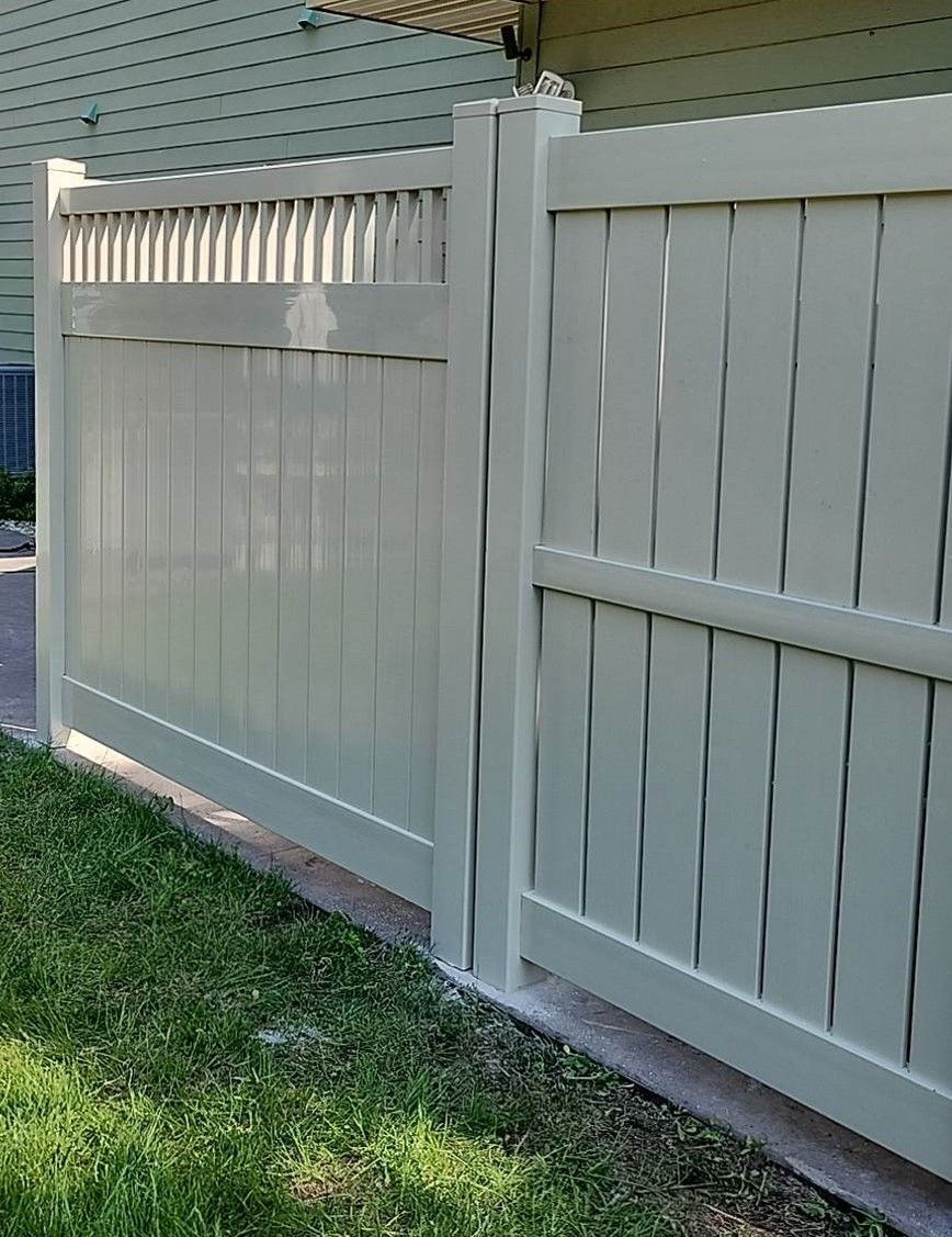A white fence is sitting in the grass next to a house.