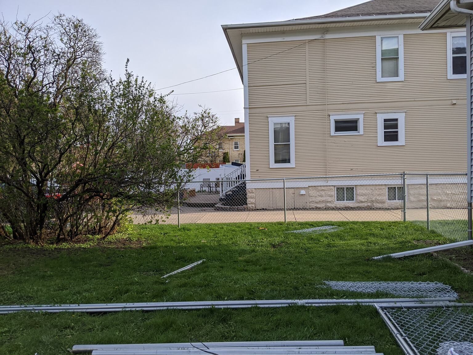 A backyard with a chain link fence and a house in the background