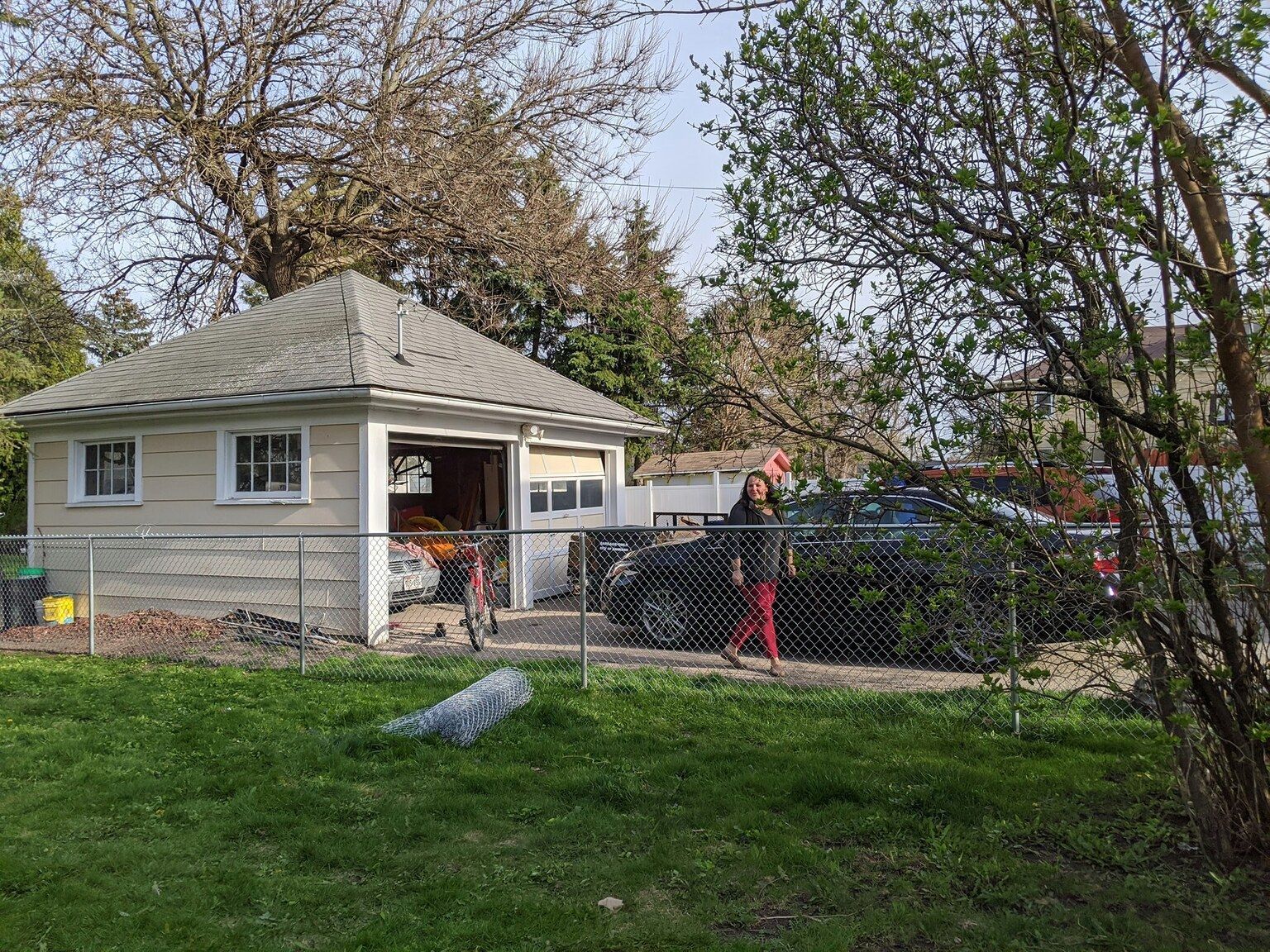 A small house with a garage and a chain link fence in the backyard.