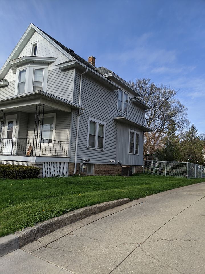 A large house with a large porch and a fence in front of it.