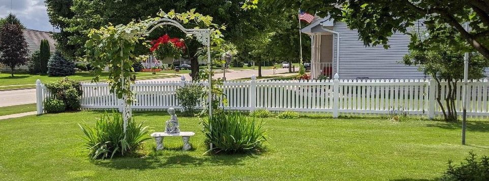 A white picket fence surrounds a lush green yard.