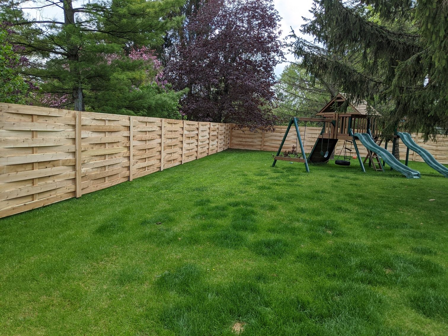 A backyard with a wooden fence and a playground.