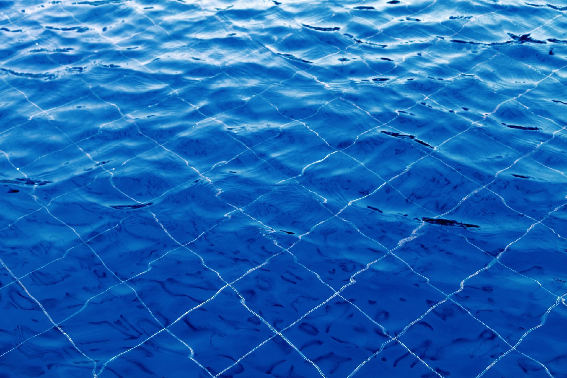 Blue water rippling over a faint diamond-patterned net or grid underwater