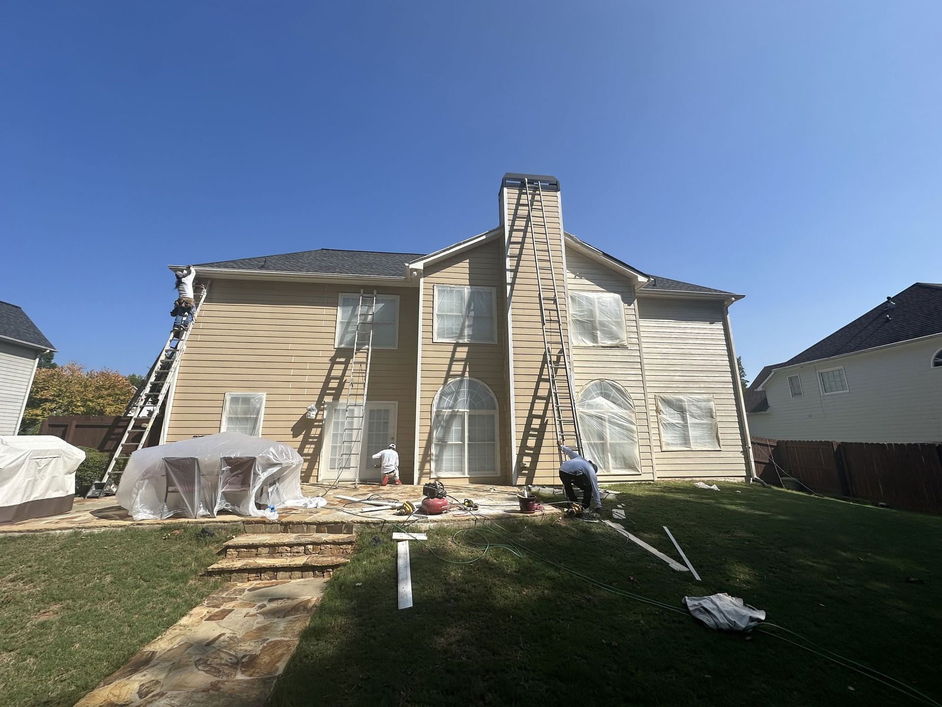 A large house is being painted by a group of people.