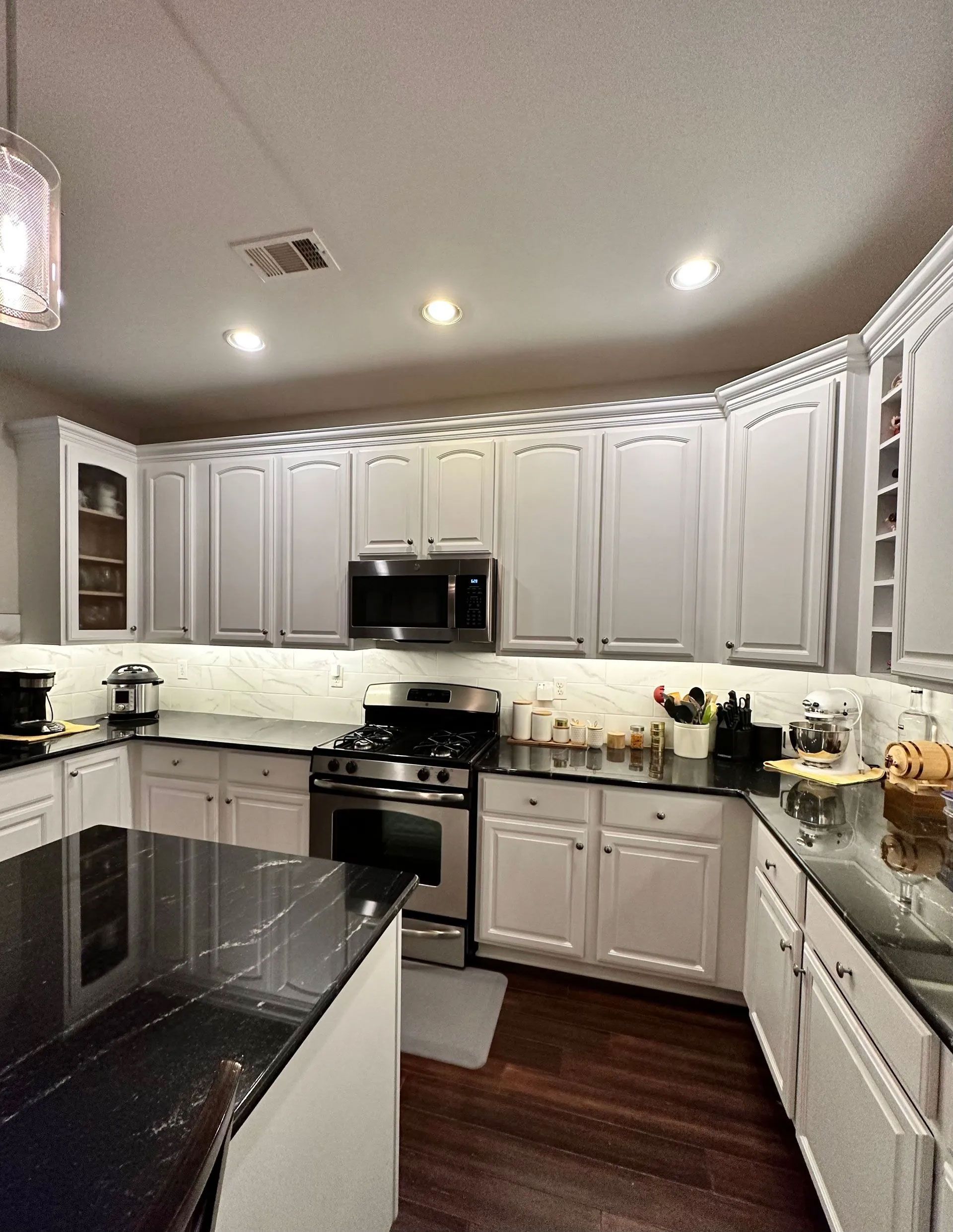 A kitchen with white cabinets and black counter tops