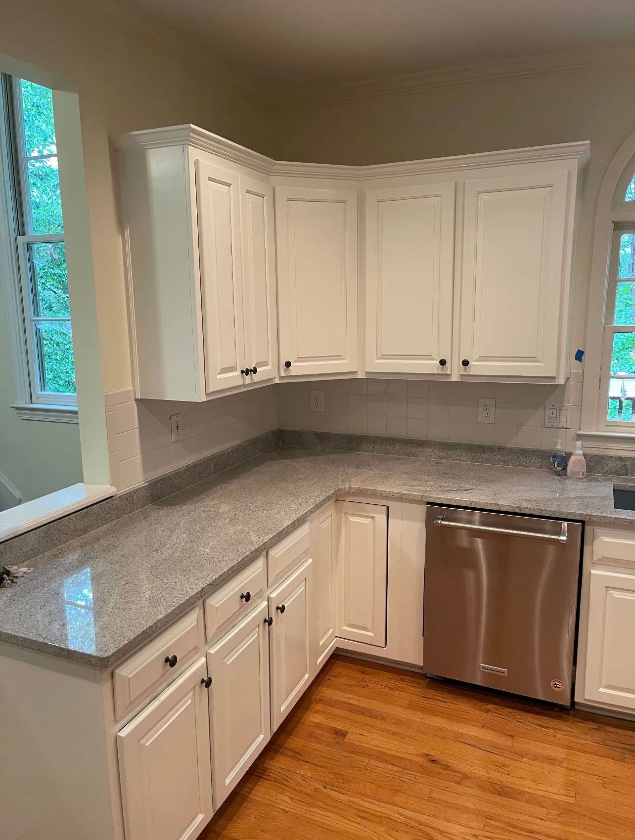 A kitchen with white cabinets , granite counter tops , and a stainless steel dishwasher.