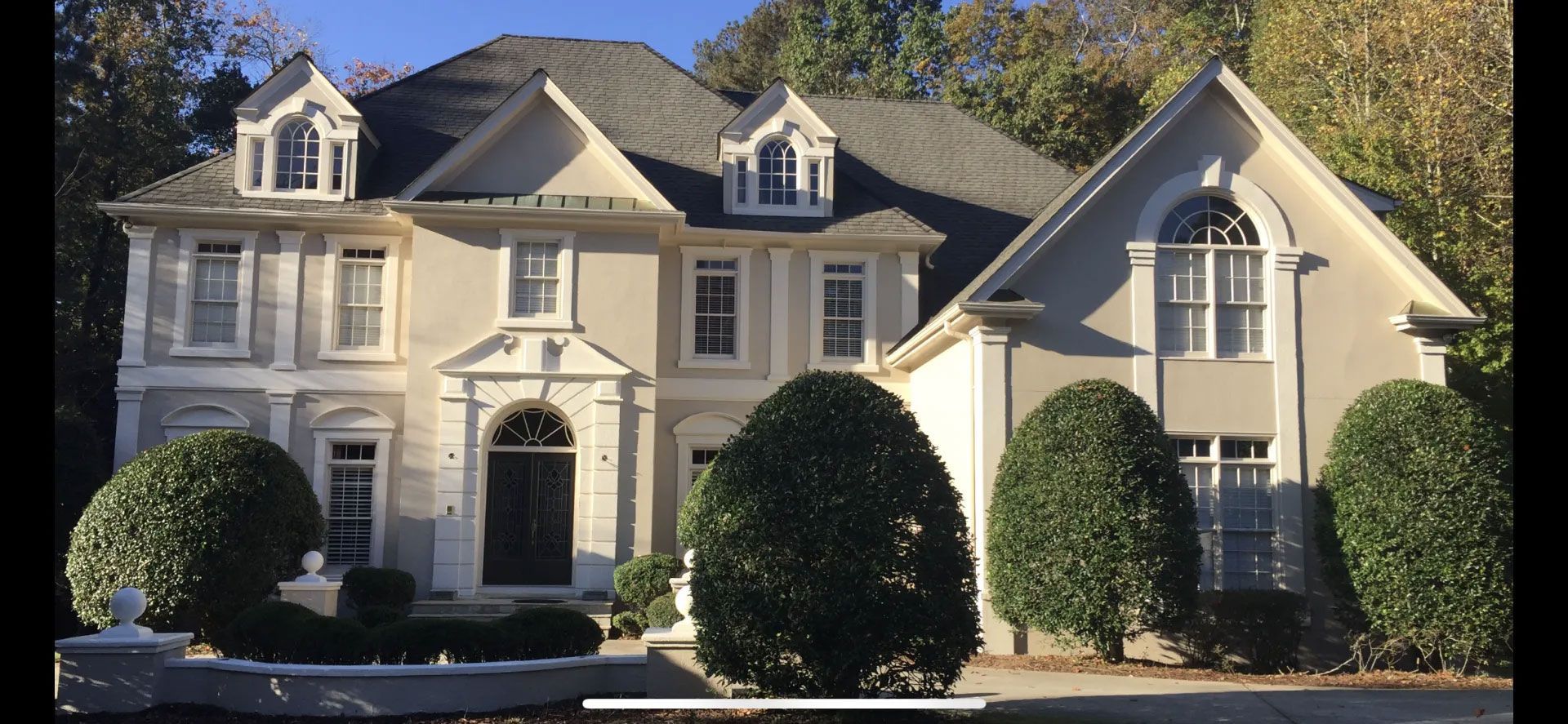 A large house with a lot of windows and bushes in front of it