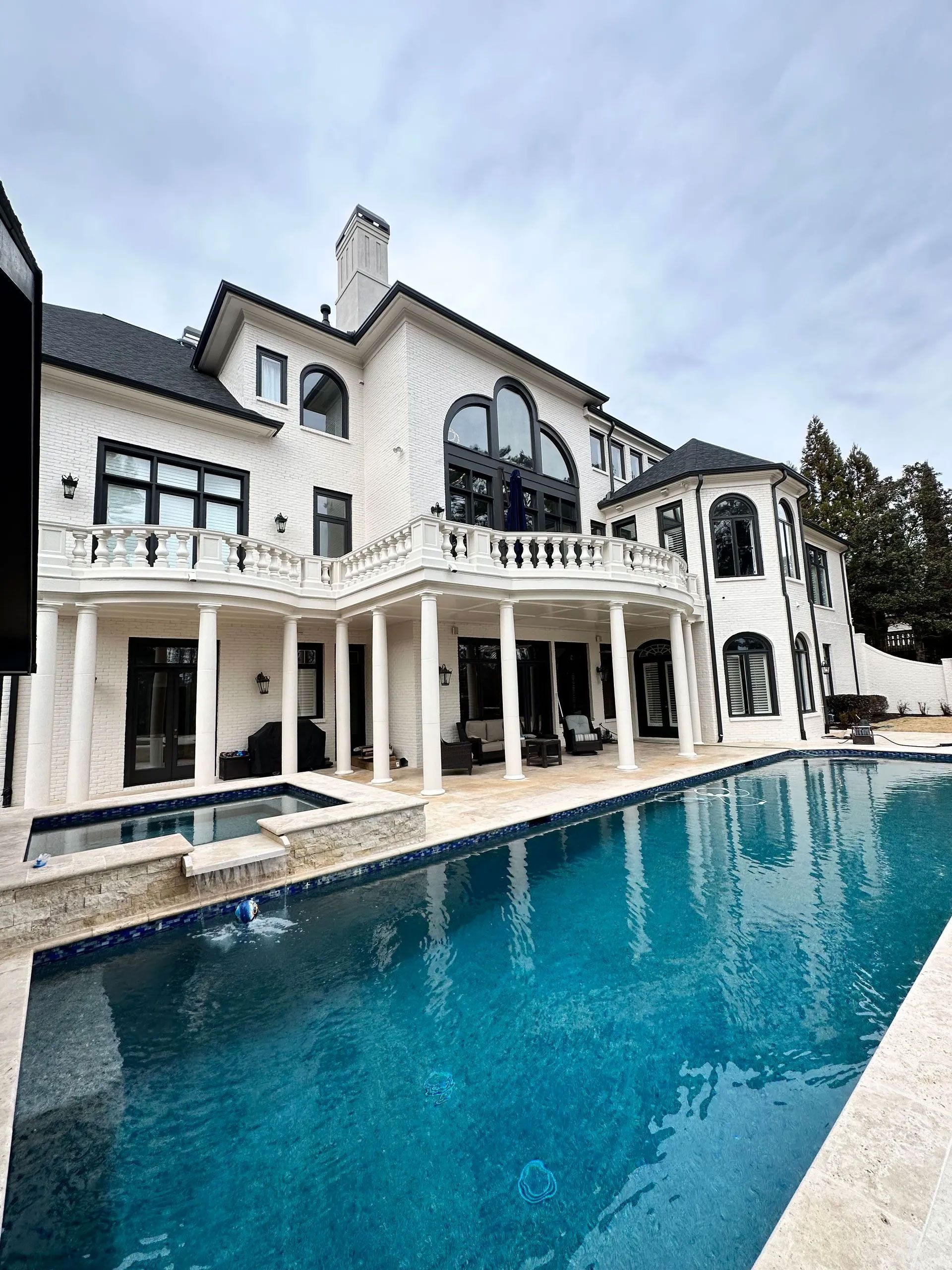 A large white house with a large swimming pool in front of it.