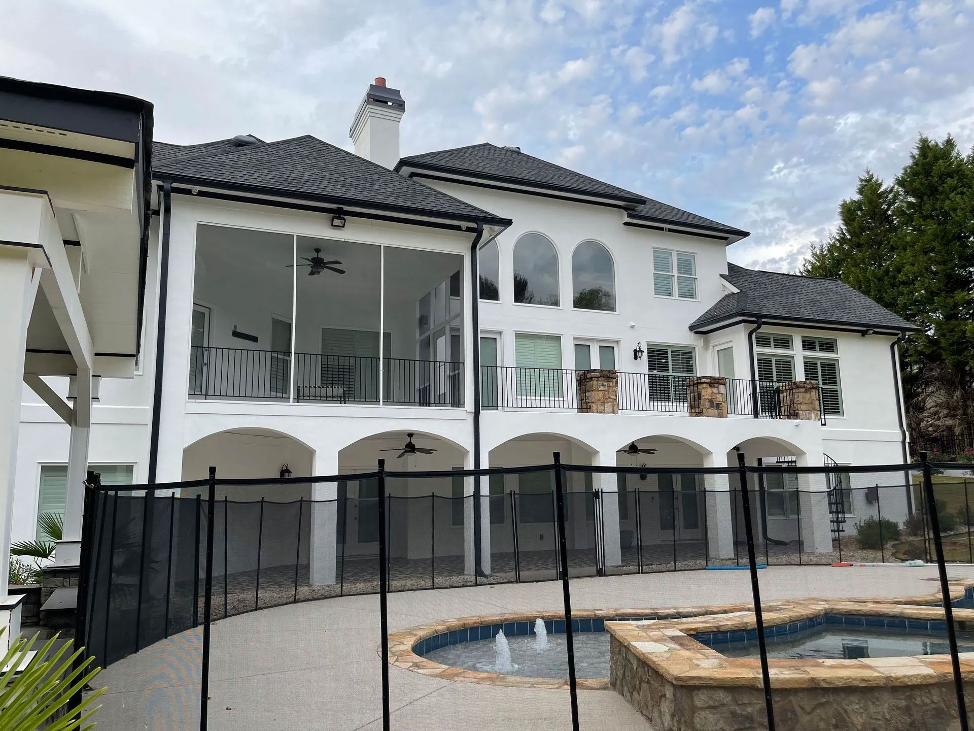 A large white house with a fence around it and a pool.