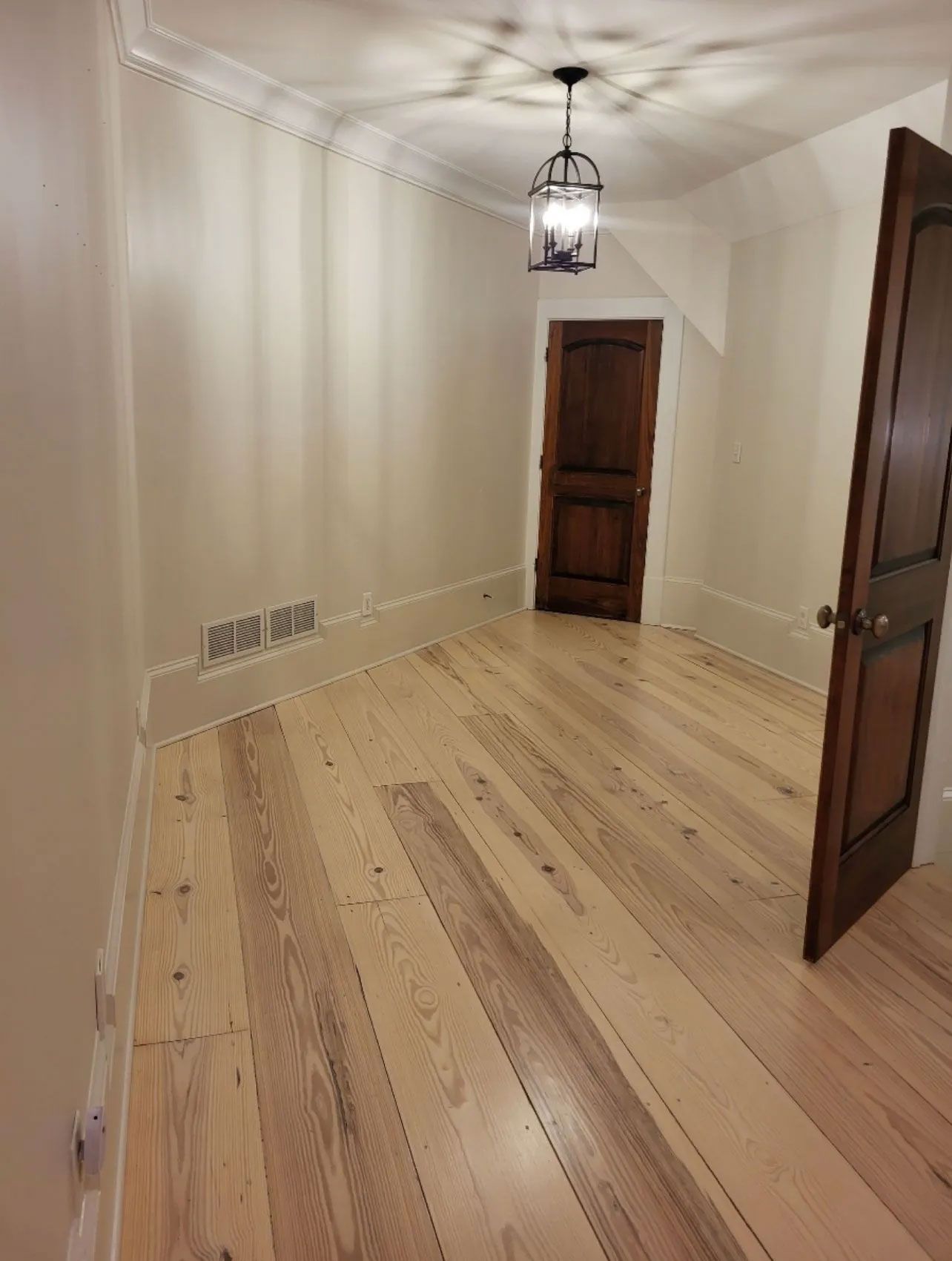 An empty room with hardwood floors and a door.