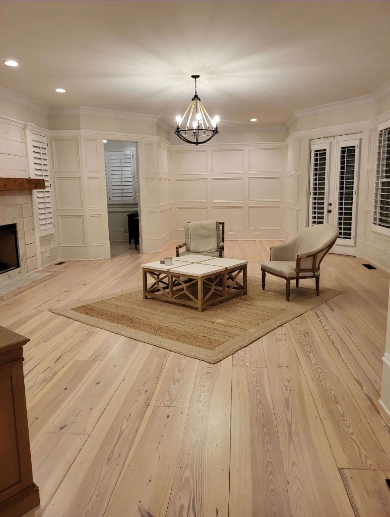 A living room with hardwood floors , chairs , a coffee table and a fireplace.
