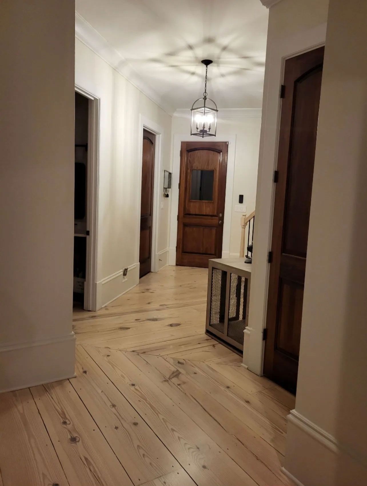 A hallway with wooden floors and doors in a house.