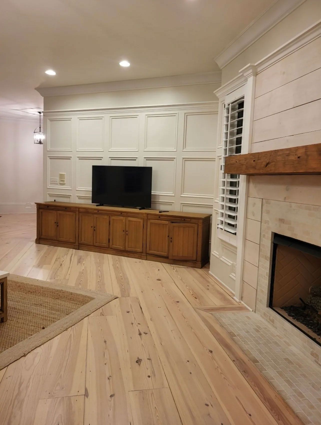 A living room with hardwood floors , a fireplace and a flat screen tv.