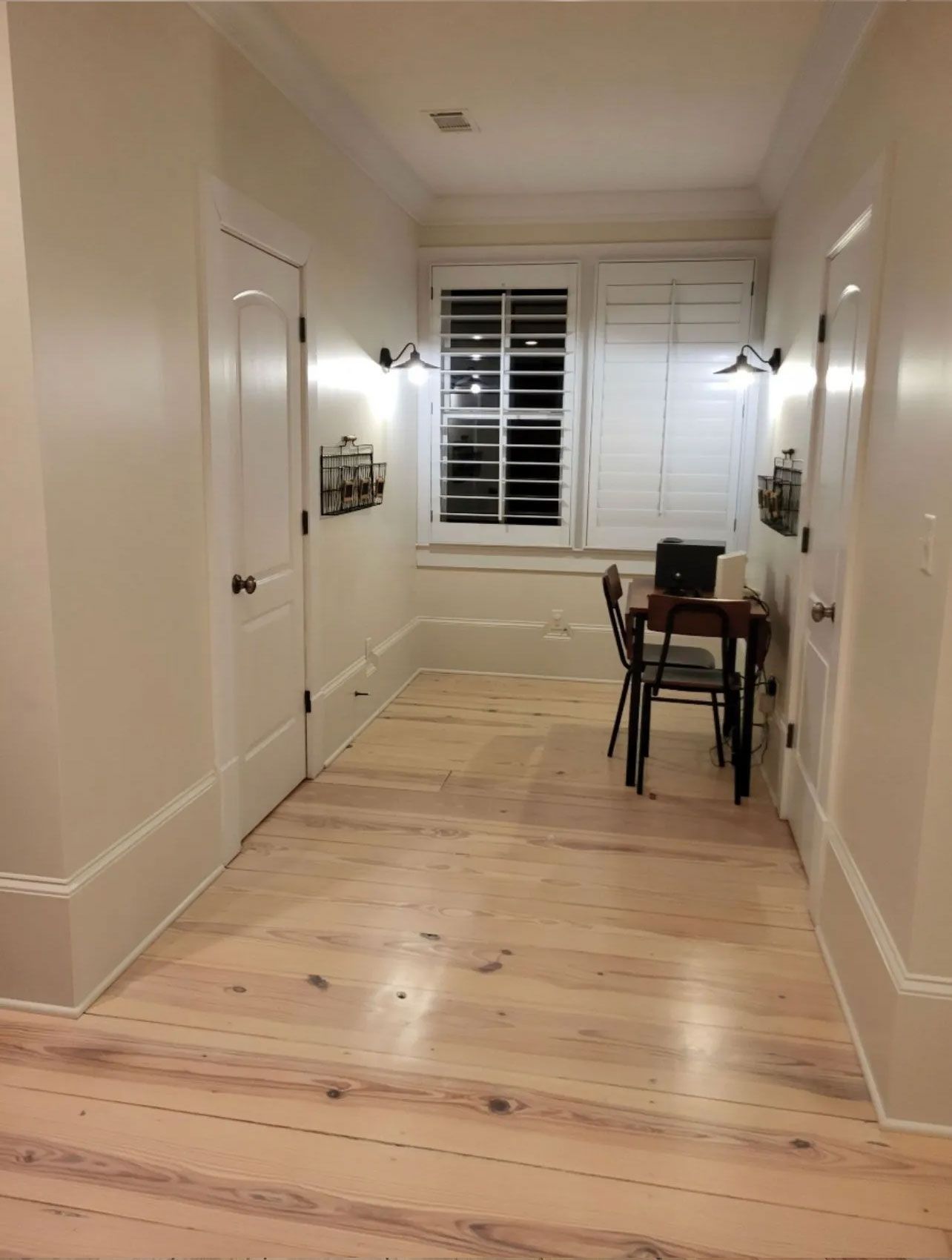 A hallway with a desk and chairs in it and a window.