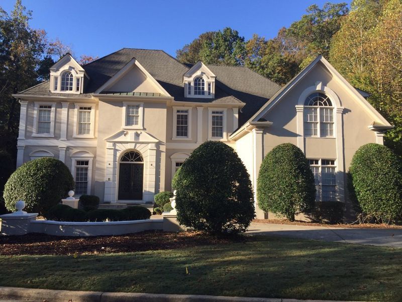 A large house with a lot of windows and bushes in front of it