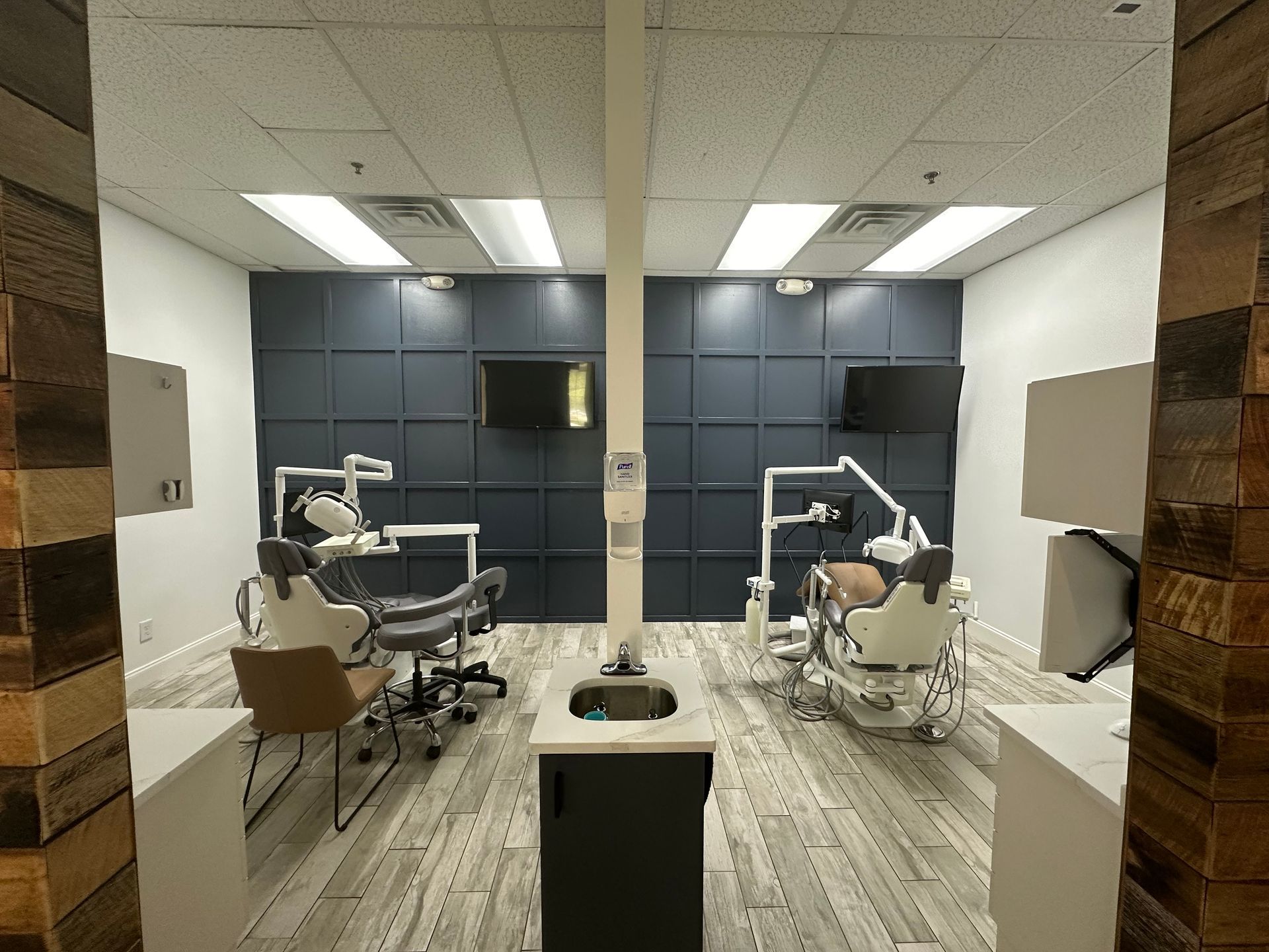 A dental office with two dental chairs and a sink.