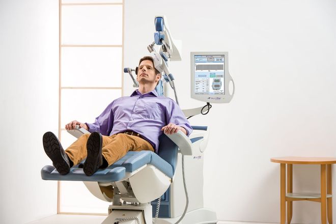 Patient reclining in a dental chair beside a dental monitor in a bright clinic room