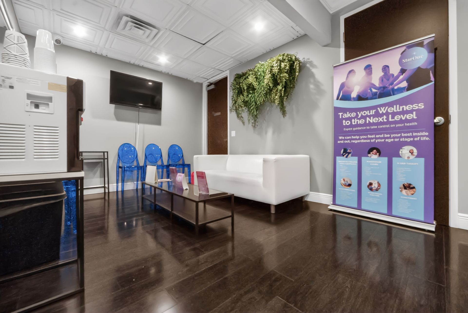 Modern lobby with white sofas, blue chairs, wall TV, and a purple promotional banner.