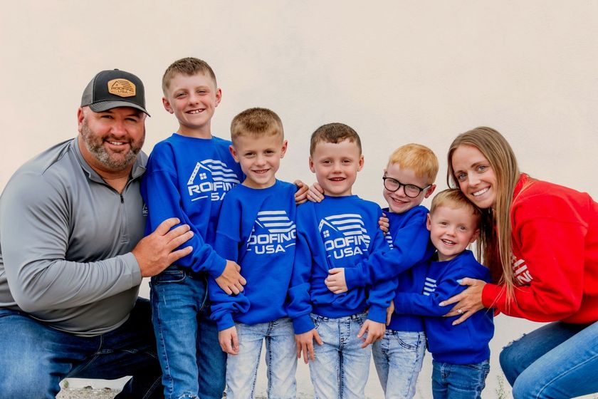 A family is posing for a picture together while wearing blue sweatshirts.
