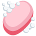 A pink oval bar of soap surrounded by white, bubbly foam.