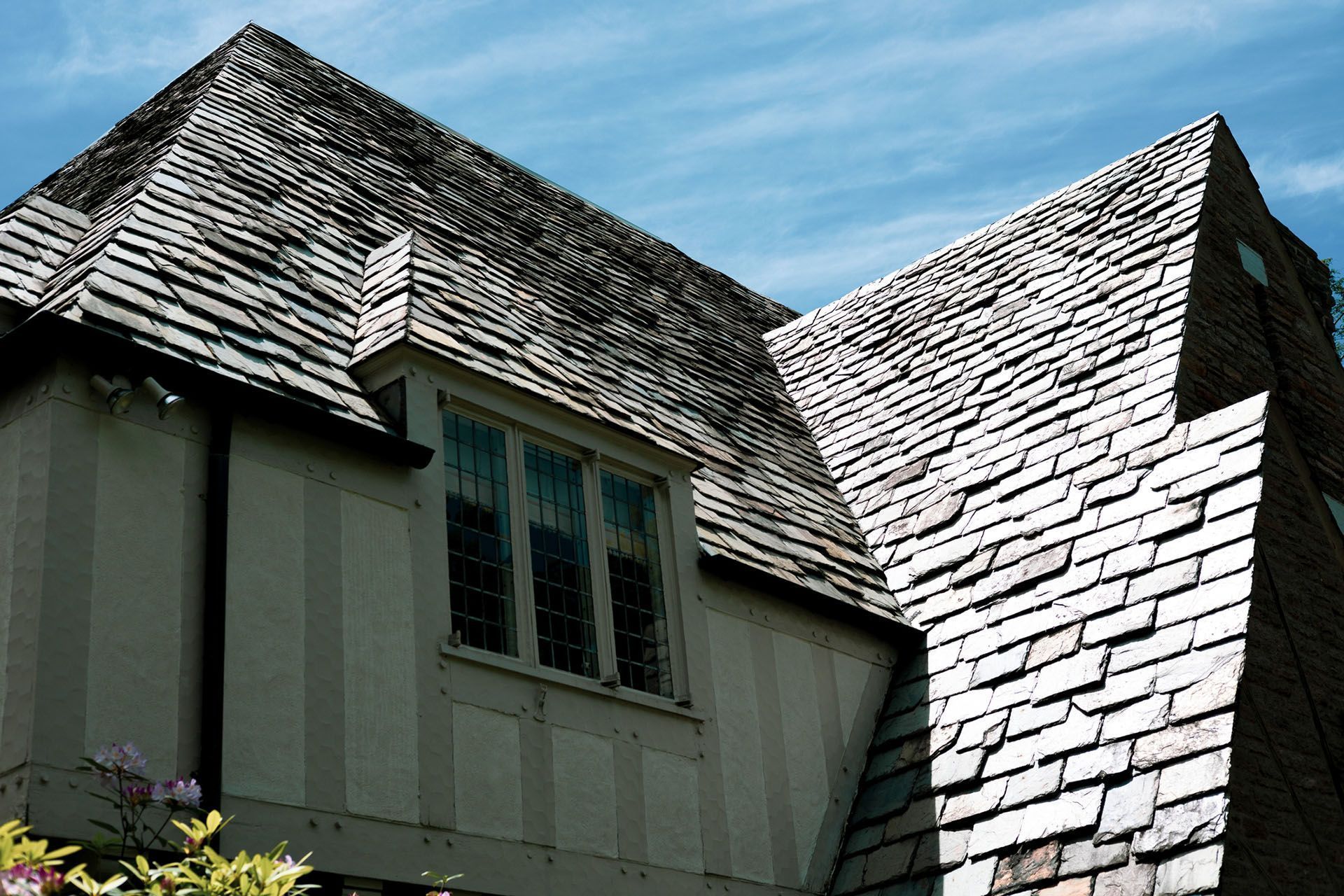 House roof with gray shingles and a dormer window under a blue sky