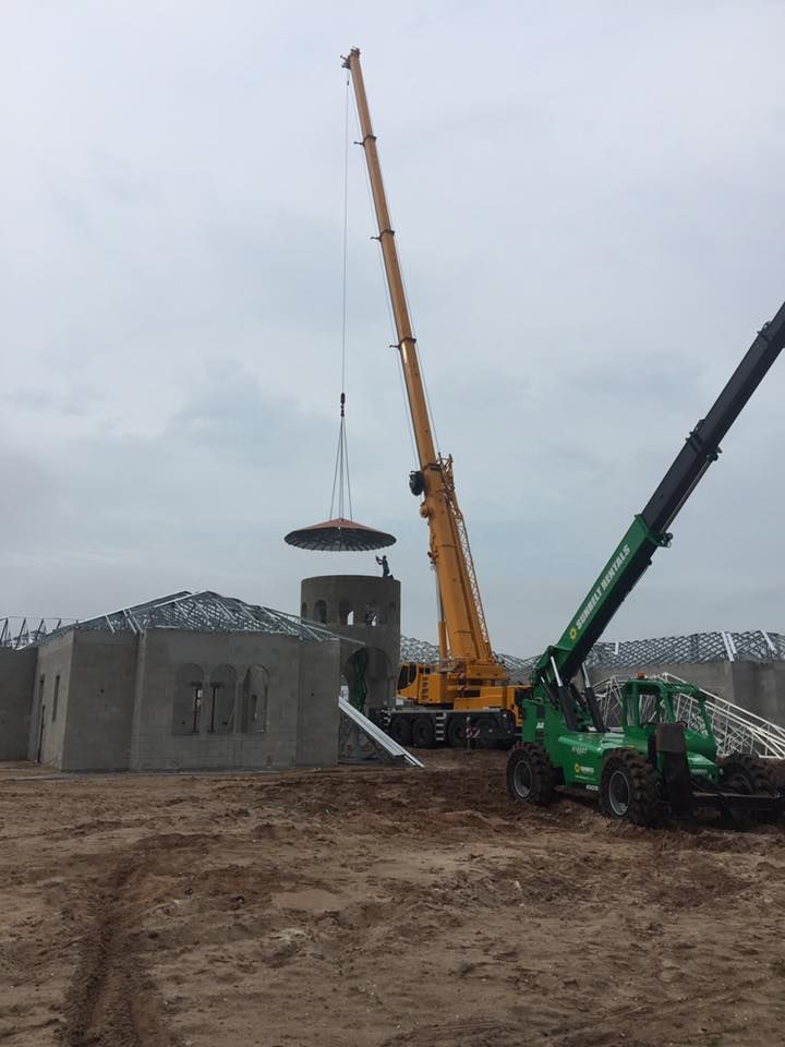 A large yellow crane is lifting a large piece of concrete.