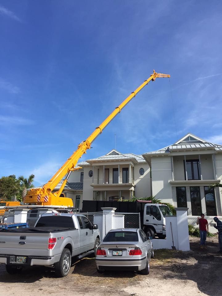 A truck with a crane on top of it is parked in front of a house.