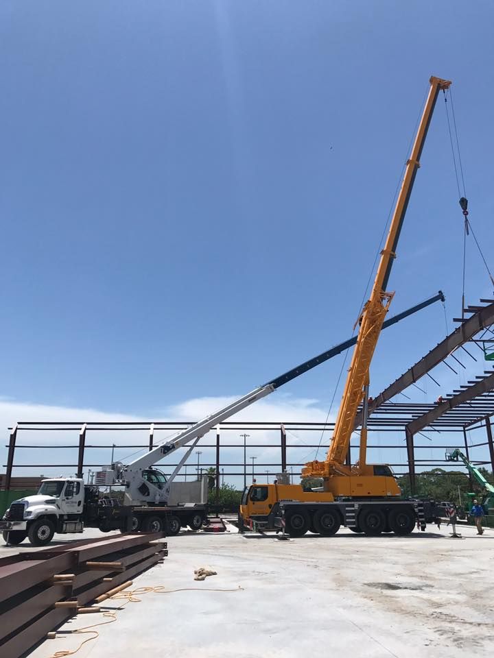A large yellow crane is working on a building under construction