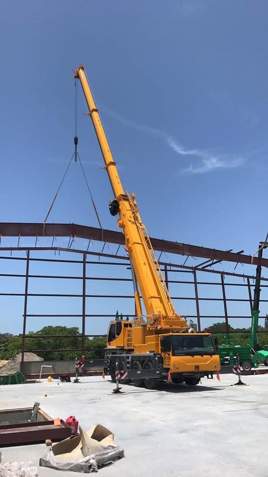 A large yellow crane is working on a building under construction.