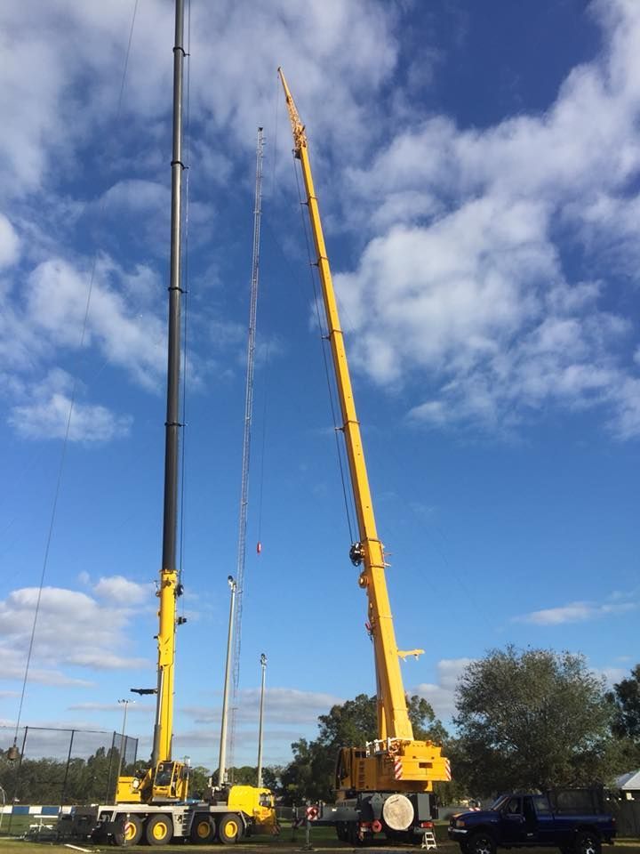 Two large yellow cranes are parked in a parking lot