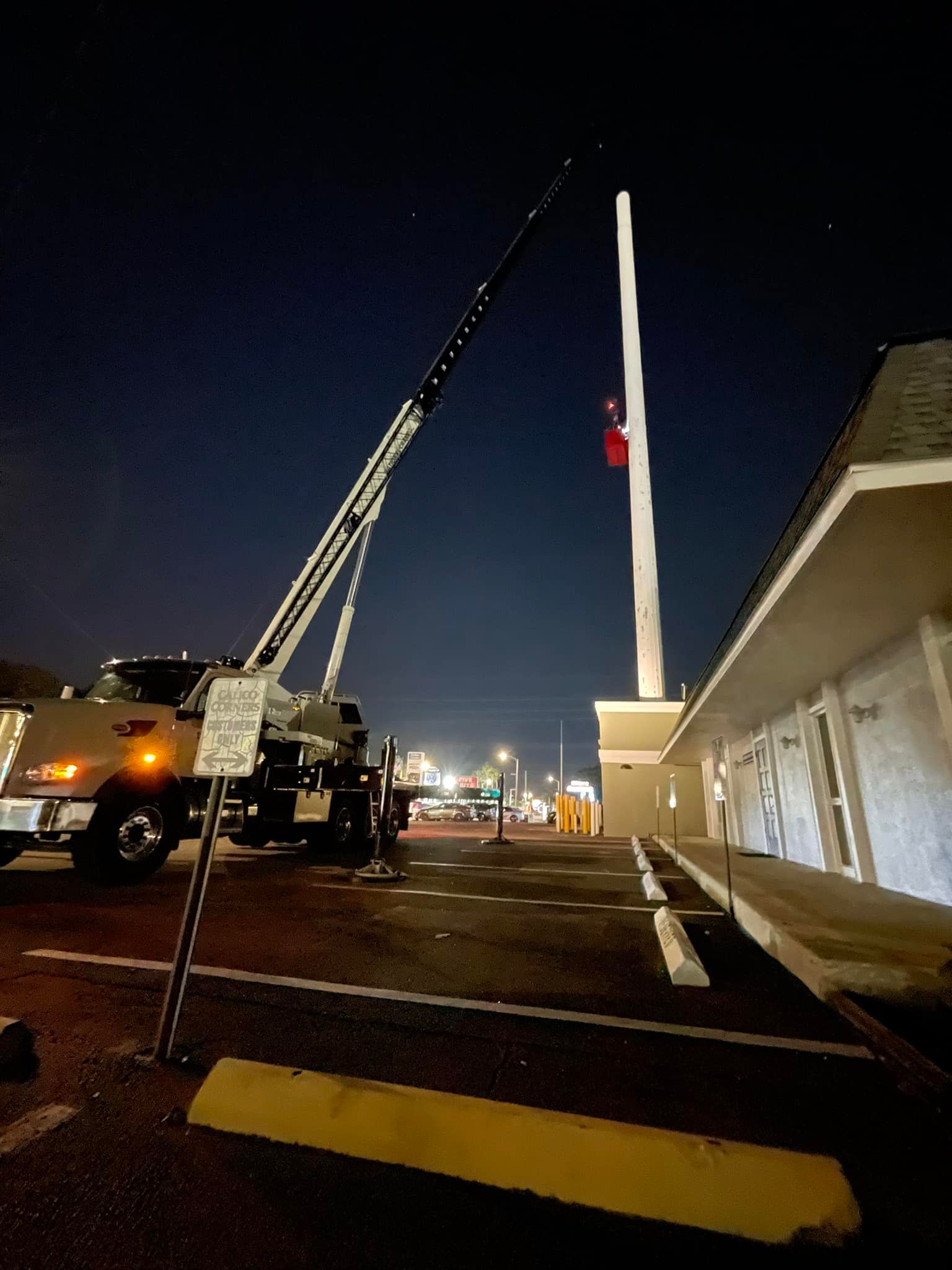A truck with a crane attached to it is parked in front of a building at night.
