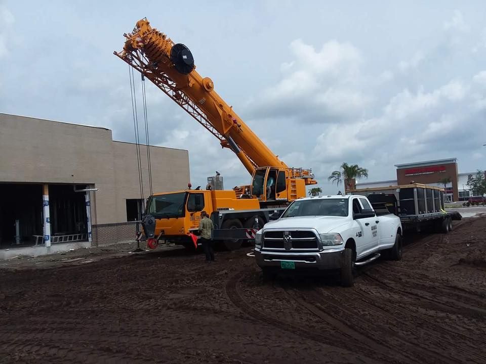 A white truck is parked next to a yellow crane
