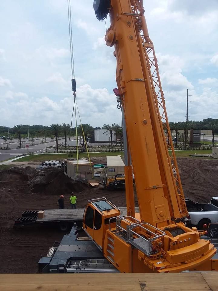 A large yellow crane is lifting a container in a construction site.
