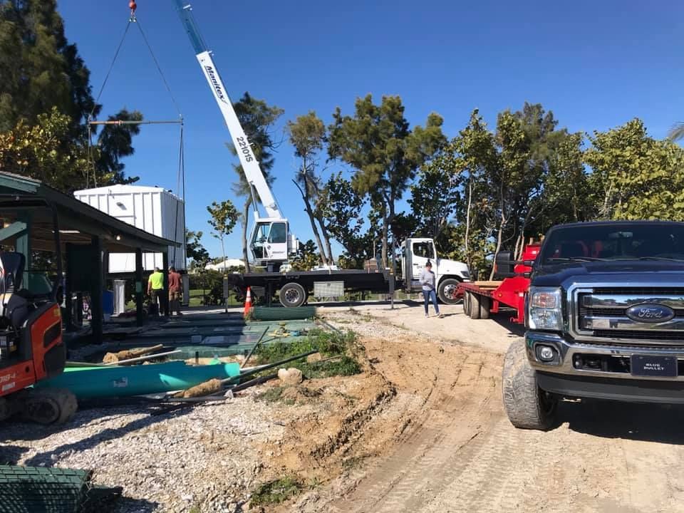 A truck is parked on the side of a dirt road next to a crane.