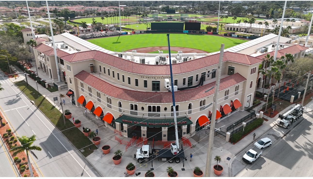An aerial view of a baseball stadium with cars parked in front of it