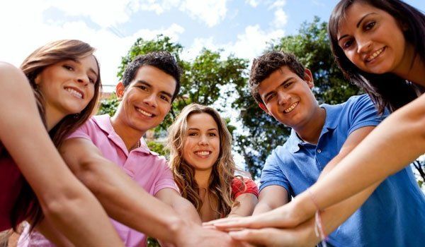 A group of young people are putting their hands together.