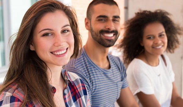 A group of young people are sitting next to each other and smiling for the camera.