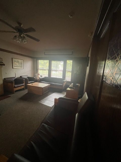 A living room with a couch and chairs and a ceiling fan