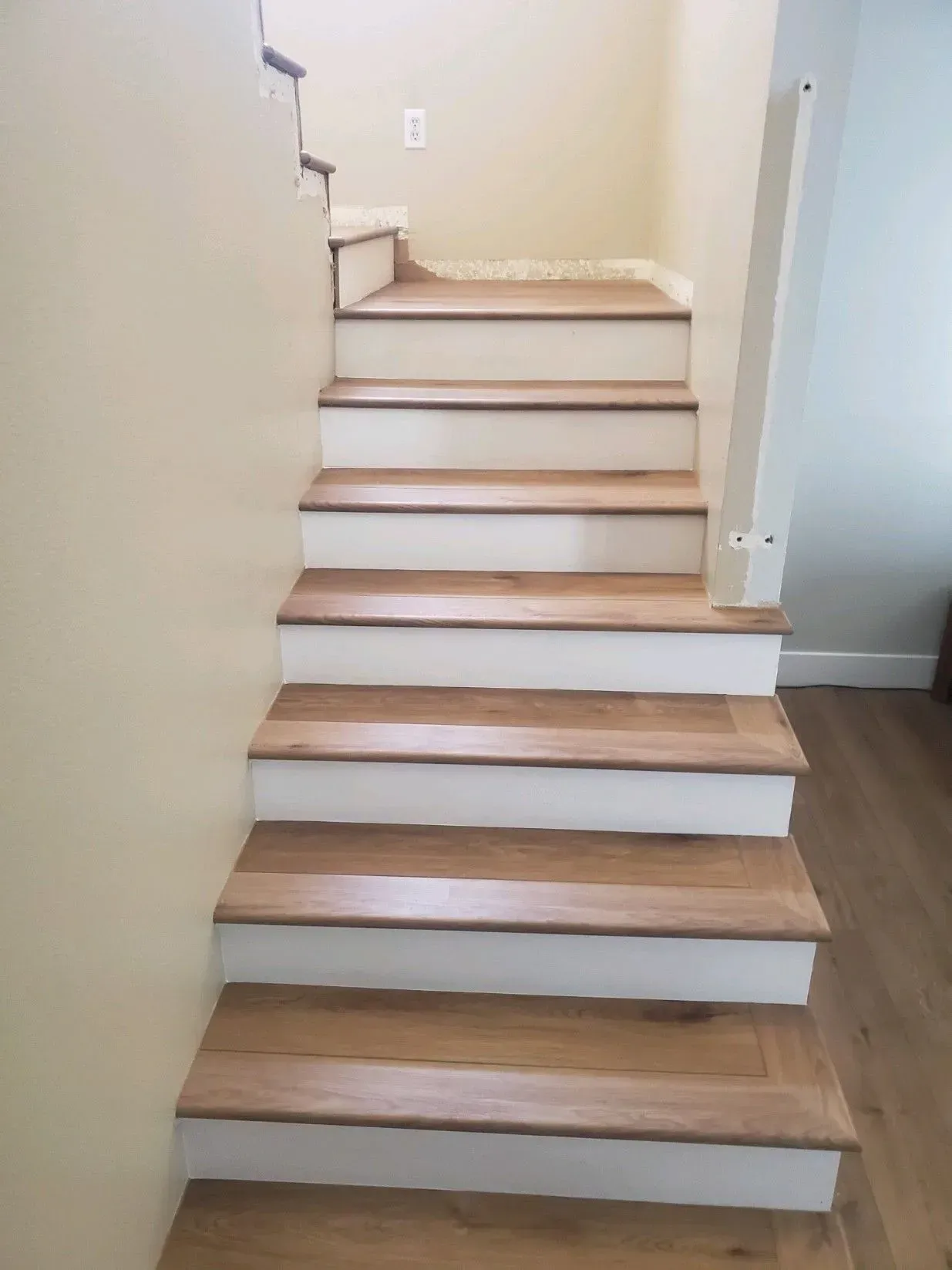A straight wooden staircase with white risers and natural wood treads leading to an upper floor.