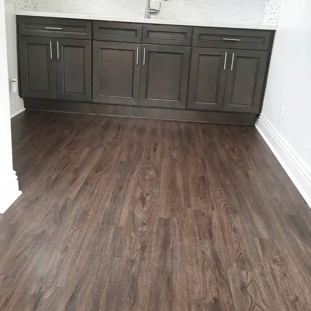 A dark wood vanity with cabinets and drawers set against a white tiled wall above a dark wood-look floor.