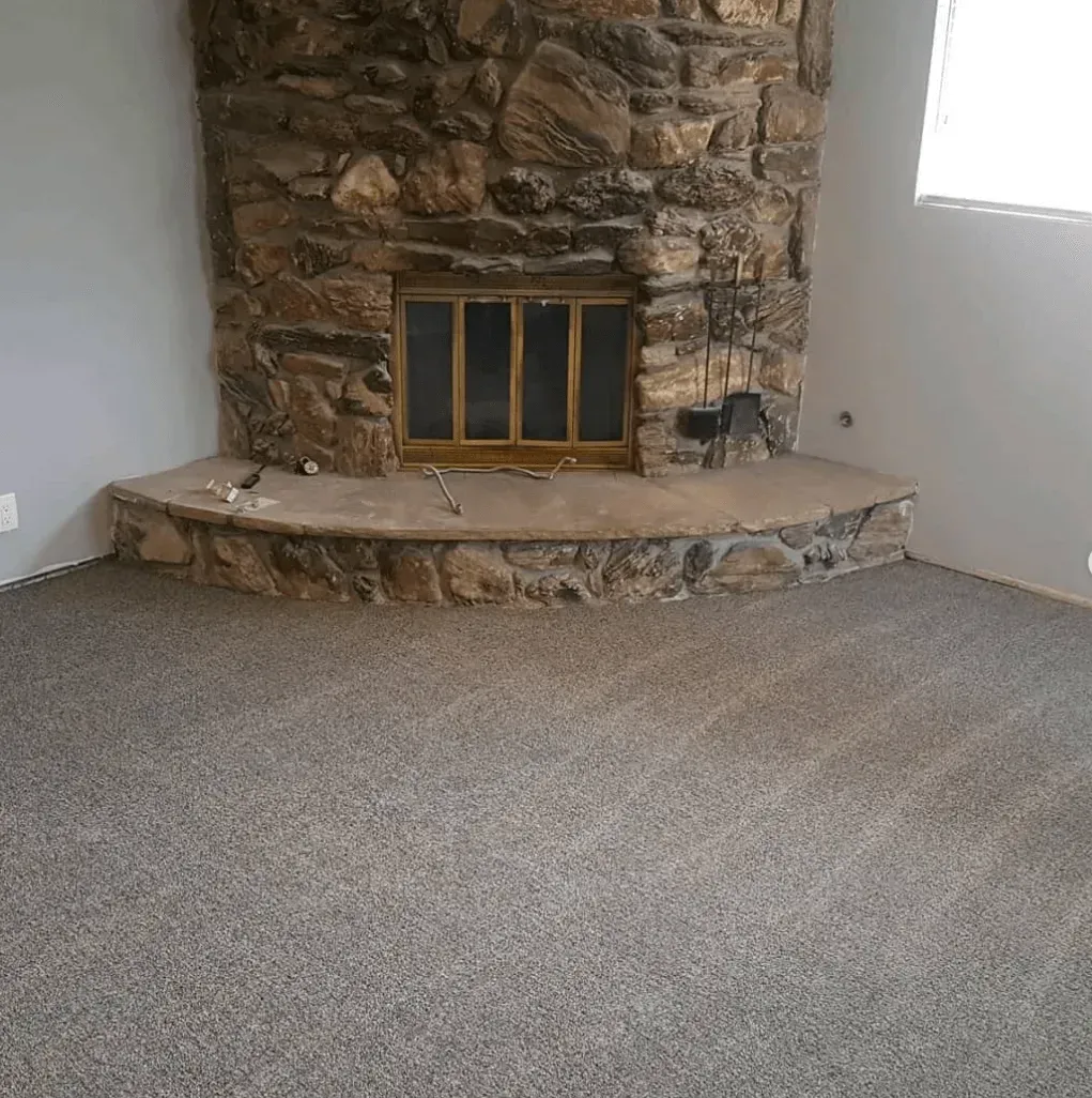 A curved stone fireplace with a gold-framed glass screen, set against a corner wall above a matching stone hearth.