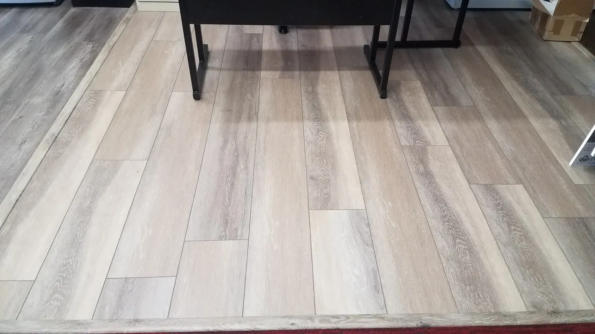 A light-toned wood-look laminate floor installation showing several planks with a natural grain texture.