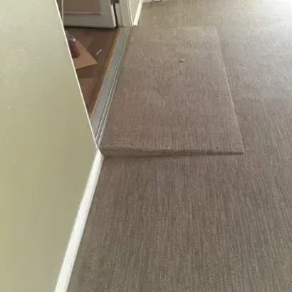 A beige carpeted threshold ramp bridging the height difference between a floor and an open doorway.