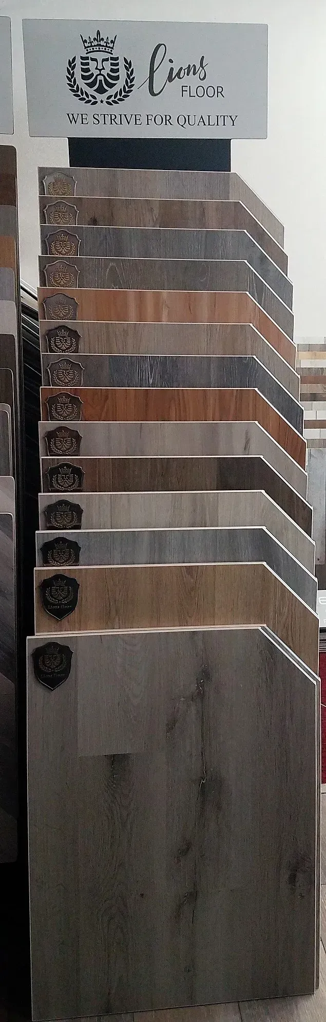 A store display rack holding a vertical stack of varied wood-look floor tile samples.