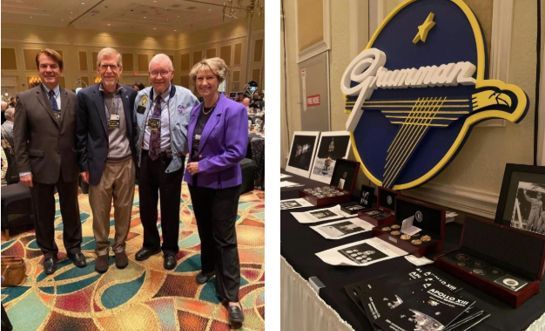 Four men in suits pose at a formal event beside a display with the “Gourmet” logo and memorabilia.