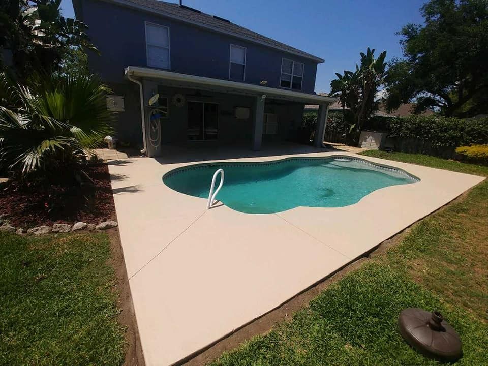 Backyard swimming pool with a white deck beside a modern house on a sunny day