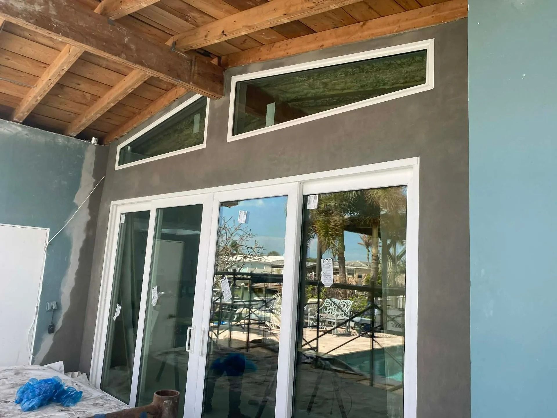 Sliding glass doors under a wood-beamed patio with blue exterior walls and narrow transom windows