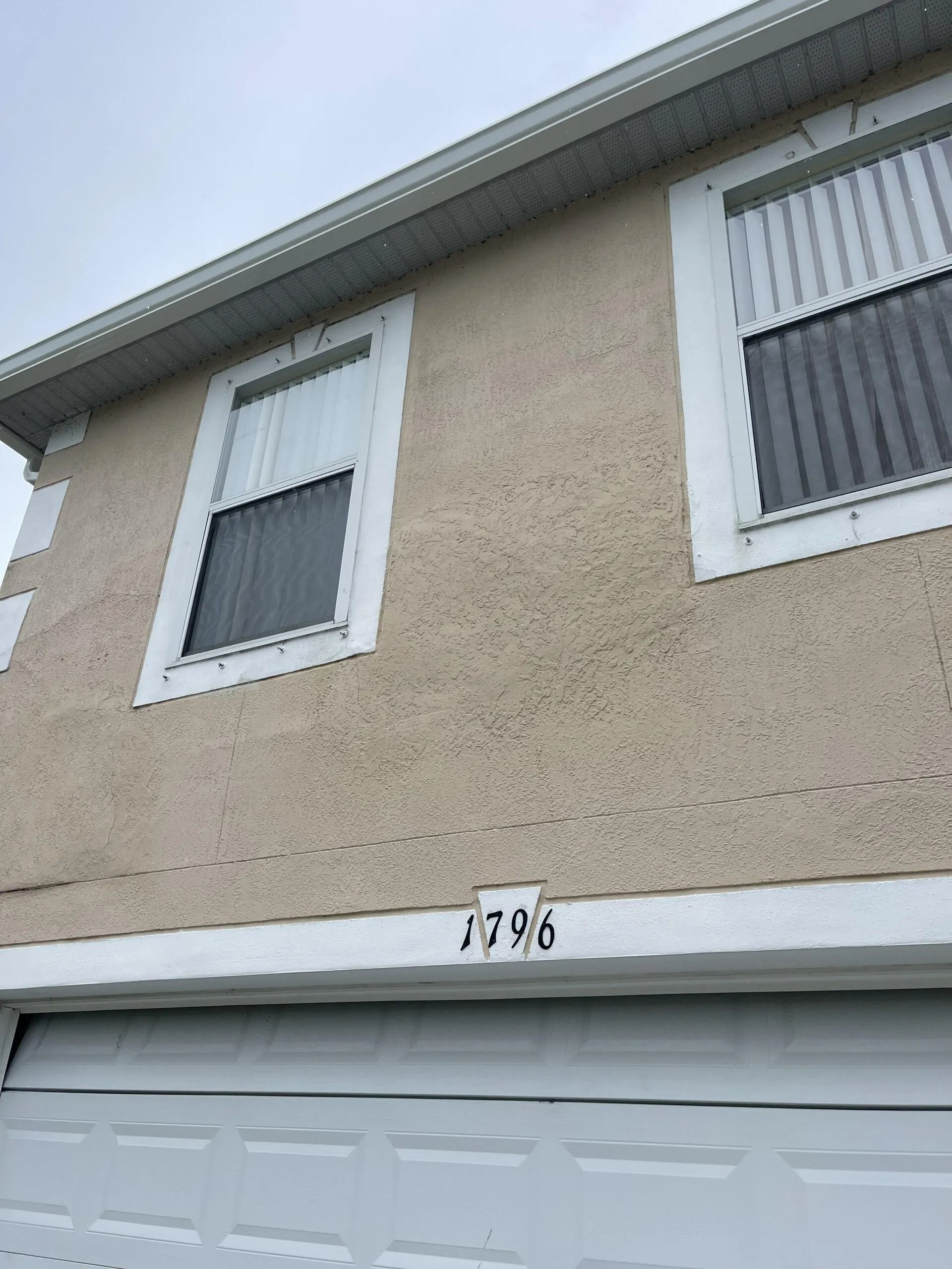 Exterior of a two-story house with beige stucco, white trim, and a garage door number 1796.